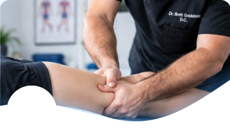 Hands applying manual soft-tissue pressure to a patient’s thigh.